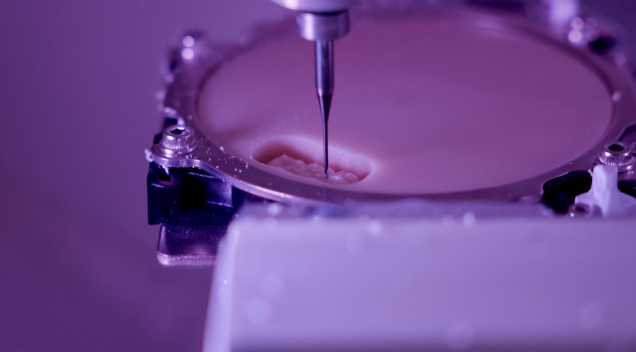Close-up of a CAD-CAM milling tool manufacturing a dental restoration.